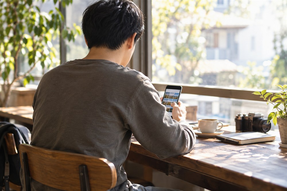 カフェでプロフィール写真を選ぶ男性の後ろ姿