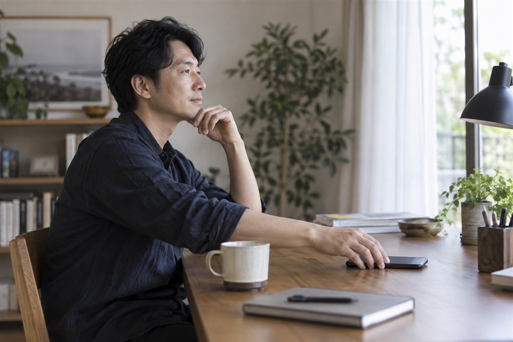スマートフォンを伏せて落ち着いて考える男性