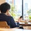 カフェでスマートフォンを持つ男性の後ろ姿